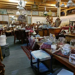 Winkelvloer vol met meubels, servies, glazen en diverse huishoudelijke artikelen op tafels en stellingen