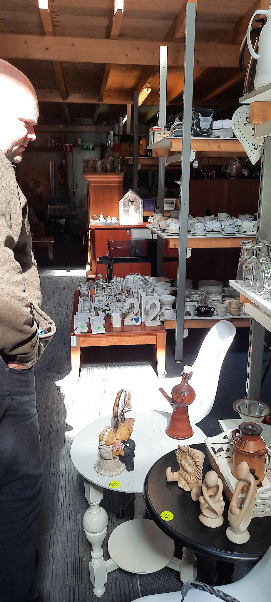 Stellingen en toonbanken met serviesgoed, kopjes, glazen en ander huishoudaartikelwerk in de kringloopwinkel