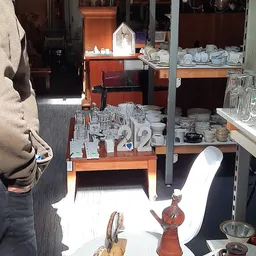 Stellingen en toonbanken met serviesgoed, kopjes, glazen en ander huishoudaartikelwerk in de kringloopwinkel