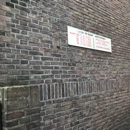 Witte informatiebord met openingstijden en contactgegevens op bakstenen muur