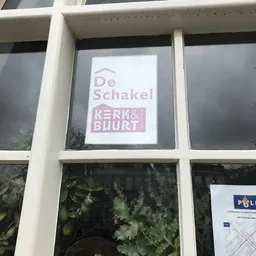 Raam met logo's van De Schakel en Kerk & Buurt