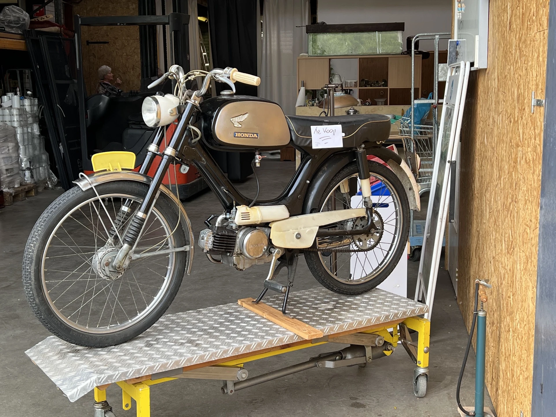 Vintage Honda brommers op gele werkplaatstafel in een werkplaats