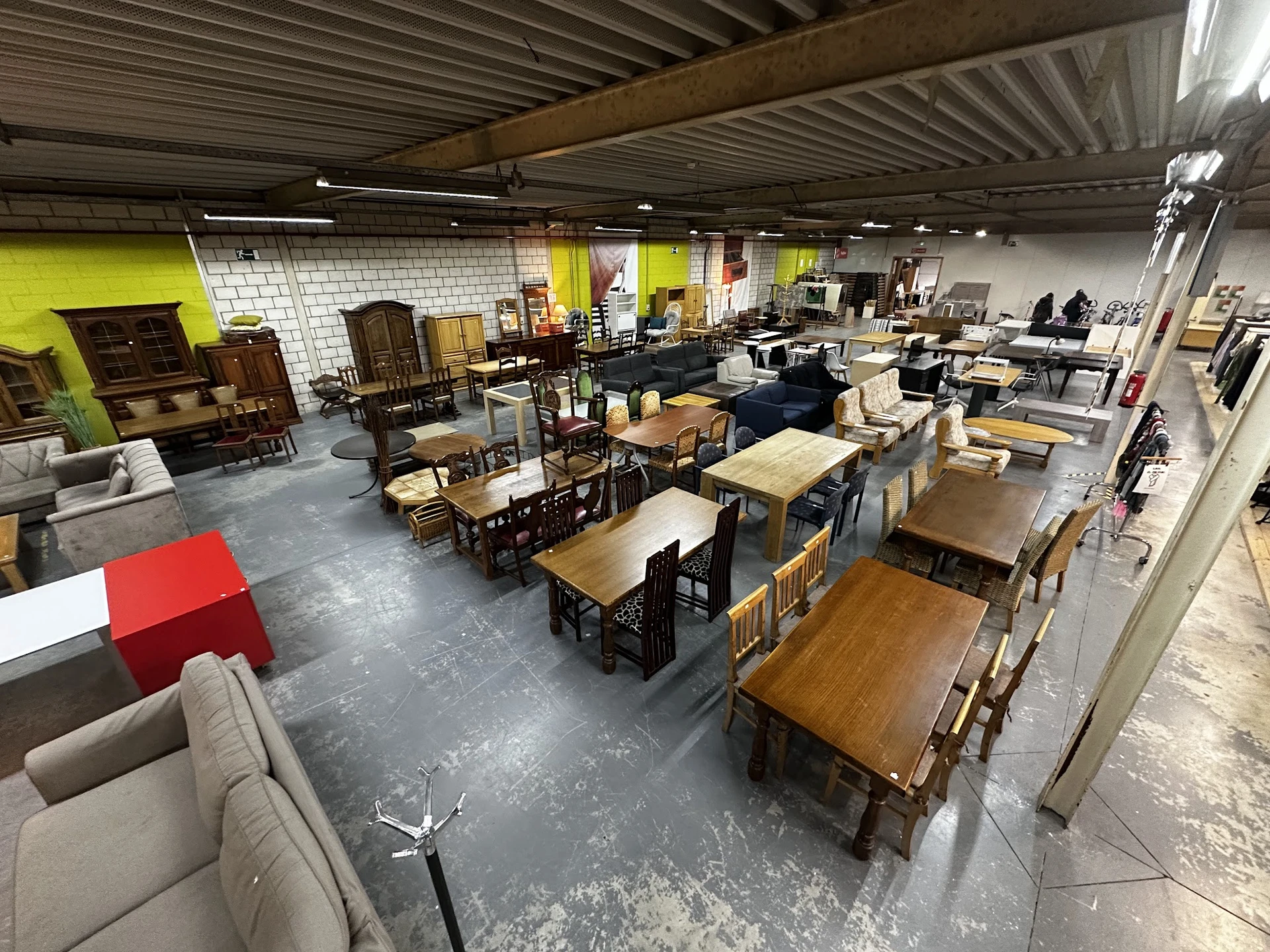 Winkelvloer met diverse meubels zoals tafels, stoelen en kasten, geel en wit geschilderde wanden