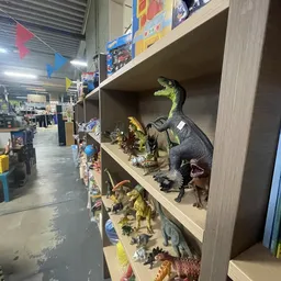 Stellingen met uitgestalde dinosaurusfiguren en speelgoedbeesten in verschillende maten en kleuren