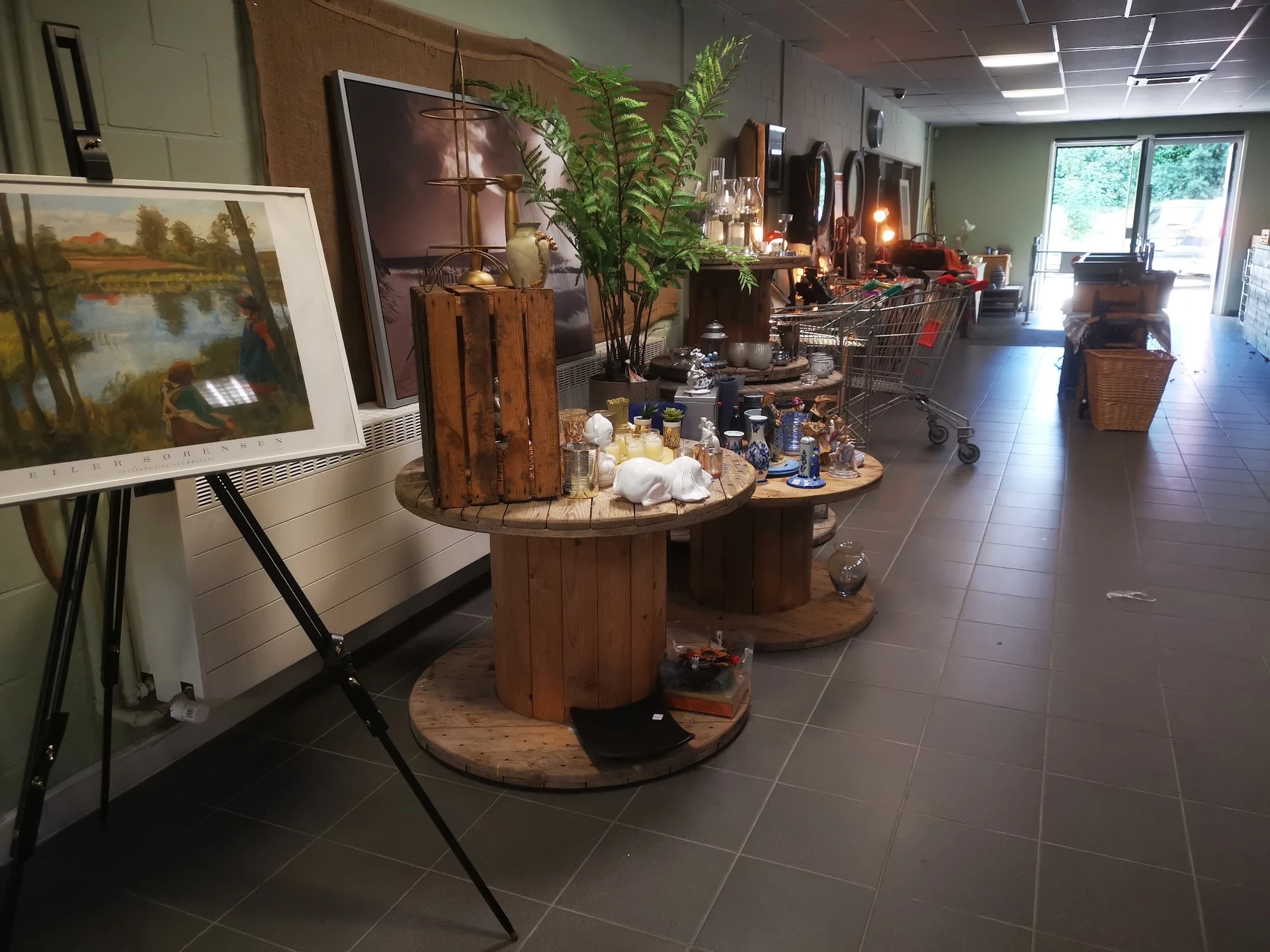 Winkelvloer met houtenDisplaytafels, kunstwerken, planten en decoratieve artikelen in kringloopwinkel