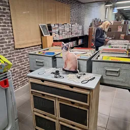 Winkelvloer met tafels, bakken en stellingen vol tweedehands spullen
