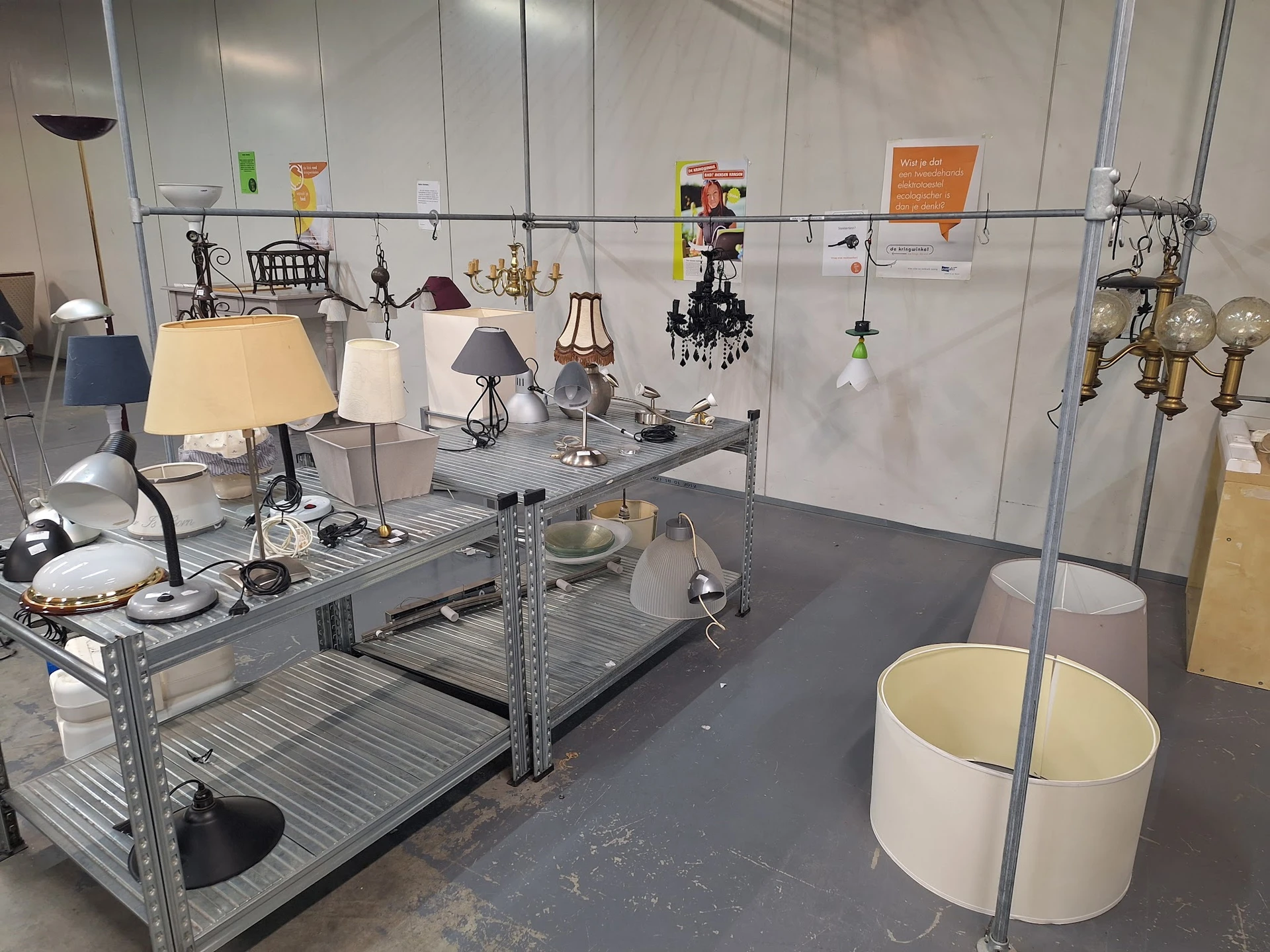 Uitgestalde lampen en hangende decoratieve items op een metalen stellage in de winkel