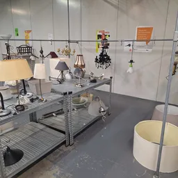 Uitgestalde lampen en hangende decoratieve items op een metalen stellage in de winkel