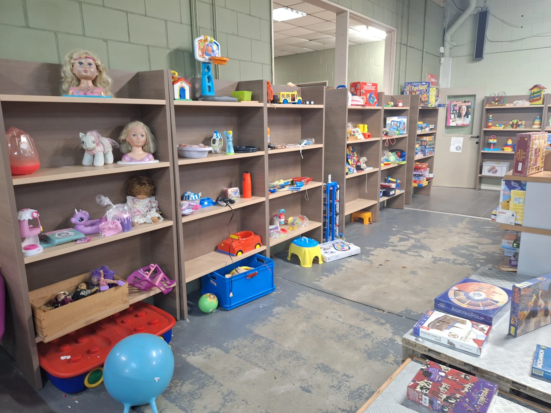 Winkelvloer met grijze stellingen vol speelgoed, poppen en kinderspeelgoed