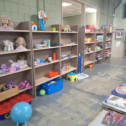 Winkelvloer met grijze stellingen vol speelgoed, poppen en kinderspeelgoed