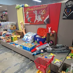 Speelgoed en kinderspeelgoed uitgestald op een platform met rode achtergrond in de winkel