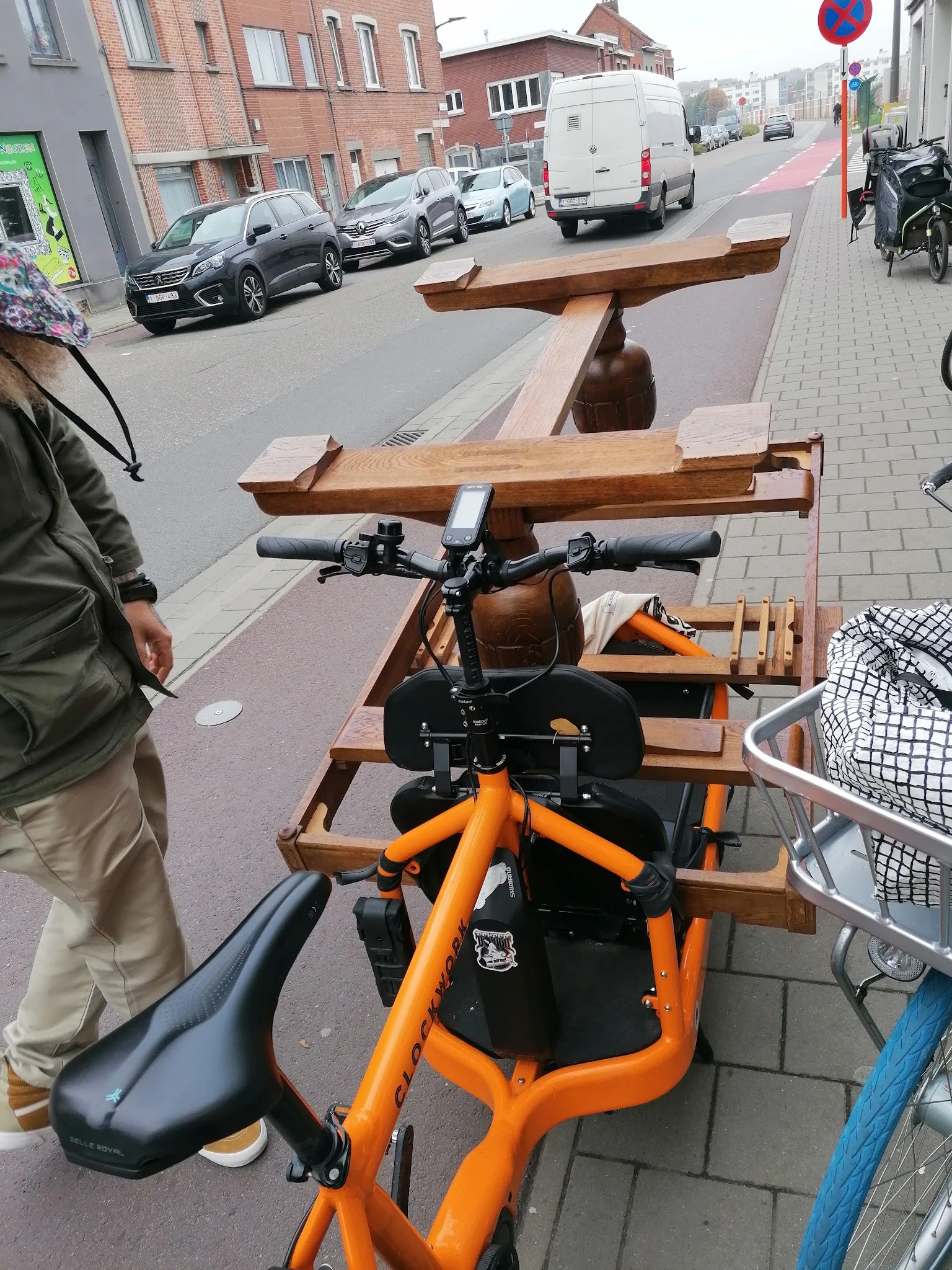Oranje en zwarte kinderspeelfiets met houten accessoires op straat