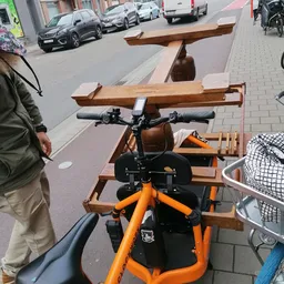 Oranje en zwarte kinderspeelfiets met houten accessoires op straat