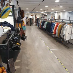 Winkelinterieur met kledingrekken vol tweedehands kleding in verschillende kleuren langs de wanden