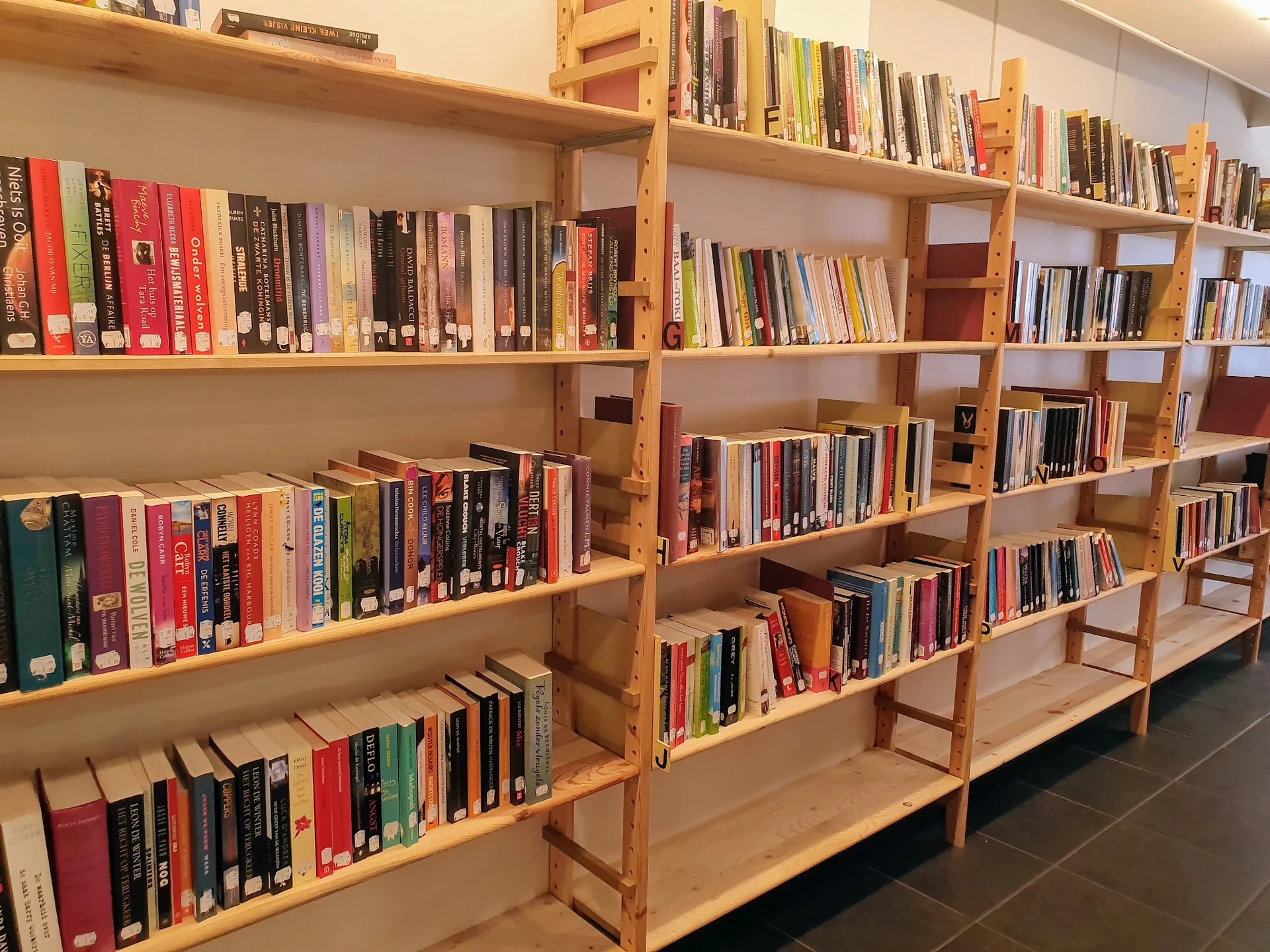 Houten boekenkasten met daarop uitgestalde tweedehands boeken in verschillende genres en kleuren