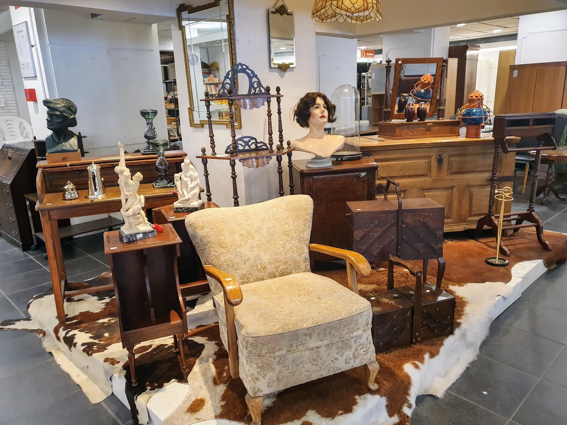 Winkelvloer met meubels en decoratieve objecten, waaronder stoelen, kasten, spiegels en kunstwerken