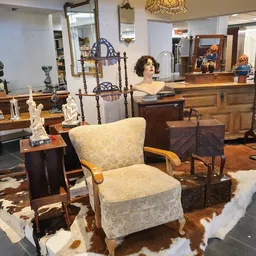 Winkelvloer met meubels en decoratieve objecten, waaronder stoelen, kasten, spiegels en kunstwerken