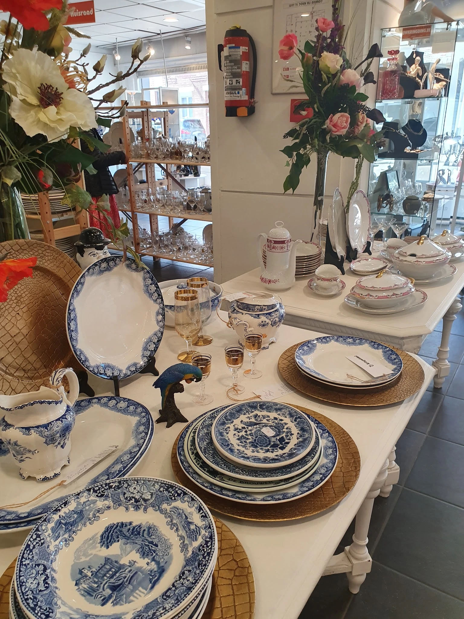 Uitgestald servies en tafelgerei met blauwe decoratie op witte ondergrond in de winkel