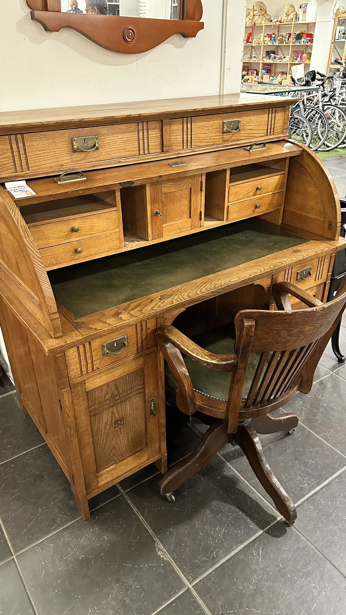Houten vintage bureau met groen blad, geopende bovenlade en bijpassende houten stoel