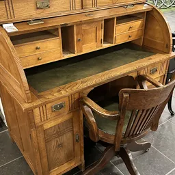 Houten vintage bureau met groen blad, geopende bovenlade en bijpassende houten stoel