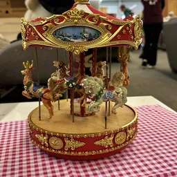 Goudkleurige draaimolen met rood en goud decoratief dak en vier paarden.
