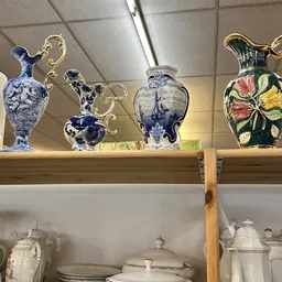 Glazen vazen en schalen met decoratieve motieven op een houten plank in de winkel
