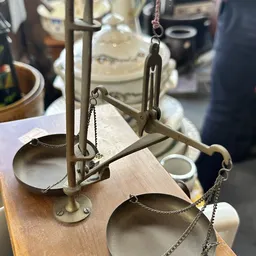 Close-up van een vintage balansweegschaal met twee metalen schalen, op houten basis