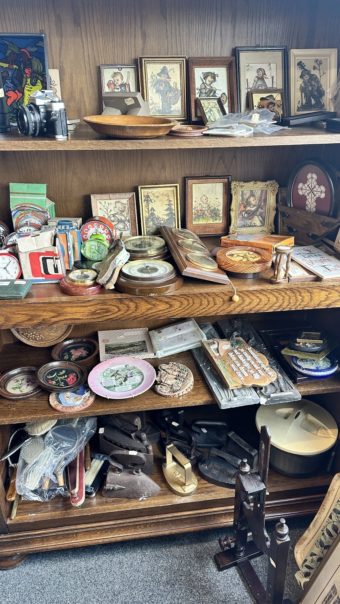 Houten schappen volgestapeld met vintage decoratieve items, borden, lijsten en antieke spullen