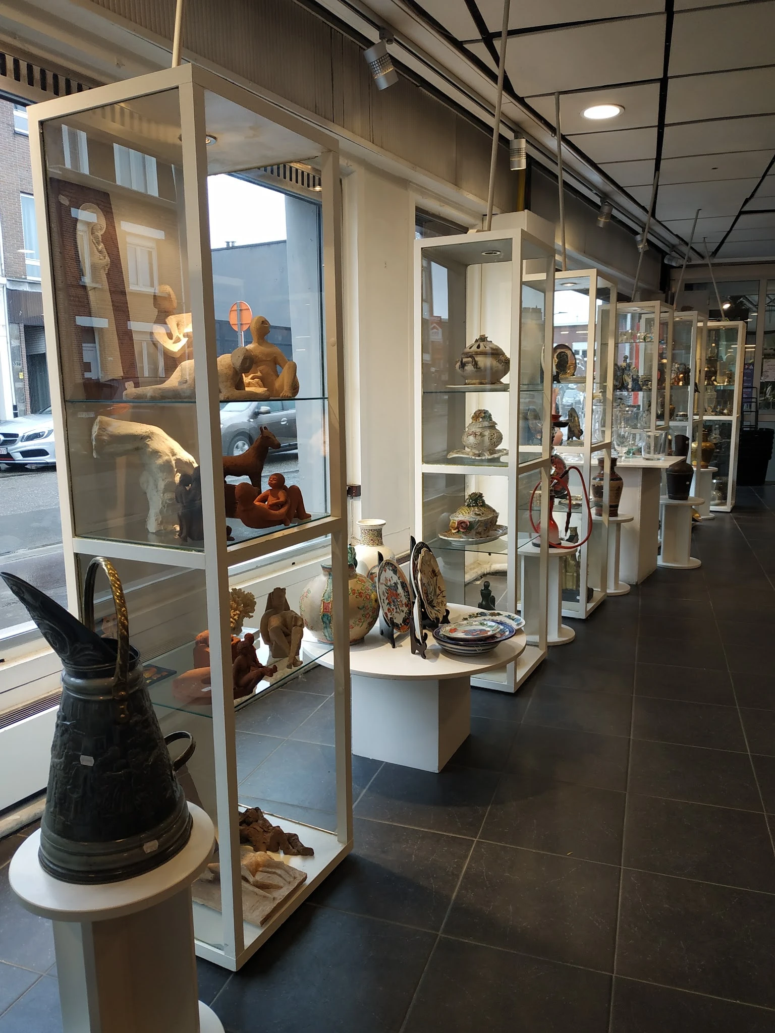 Vitrinekasten met keramiek, beelden en decoratieve voorwerpen in een kringloopwinkel