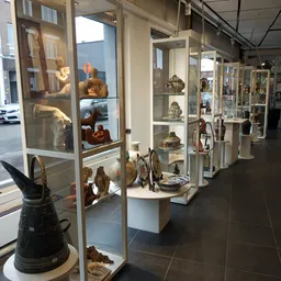 Vitrinekasten met keramiek, beelden en decoratieve voorwerpen in een kringloopwinkel