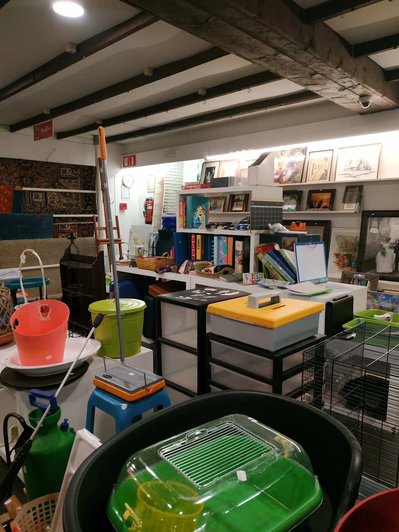 Winkelbinnenkant met werkstafels, stellingen vol boeken, kunst, decoratie en diverse tweedehands spullen