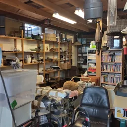 Winkelvloer met houten stellingen, boekenkasten, zitmeubels en diverse tweedehands artikelen