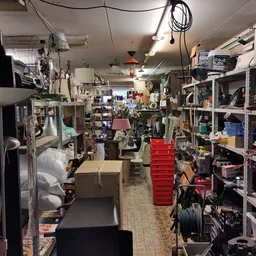 Winkelvloer van kringloopwinkel met stellingen, dozen en uiteenlopend aanbod aan tweedehands artikelen