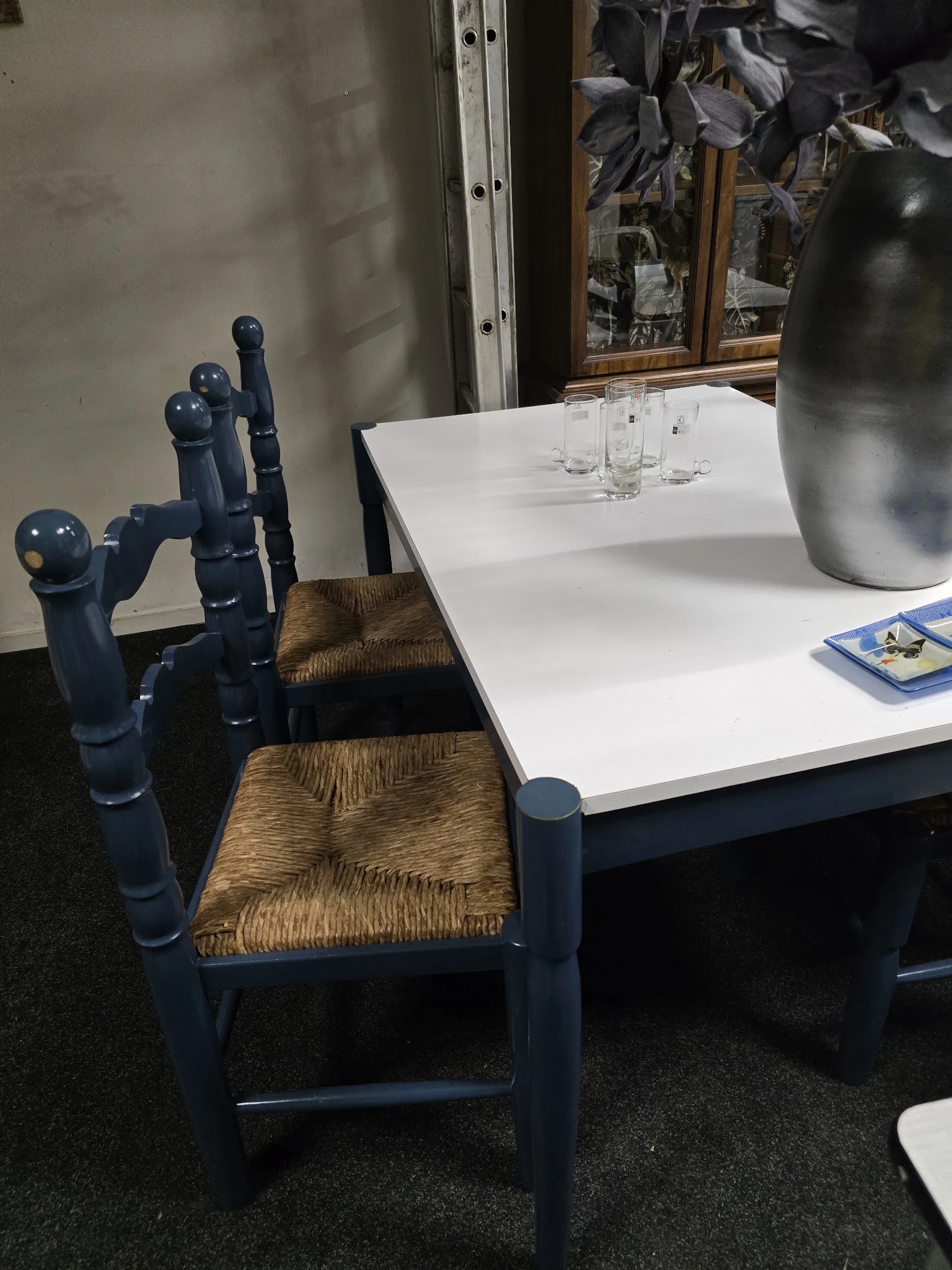 Blauwe houten stoelen met rieten zitting bij een witte tafel met glazen