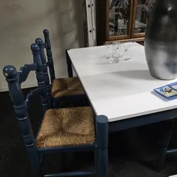 Blauwe houten stoelen met rieten zitting bij een witte tafel met glazen