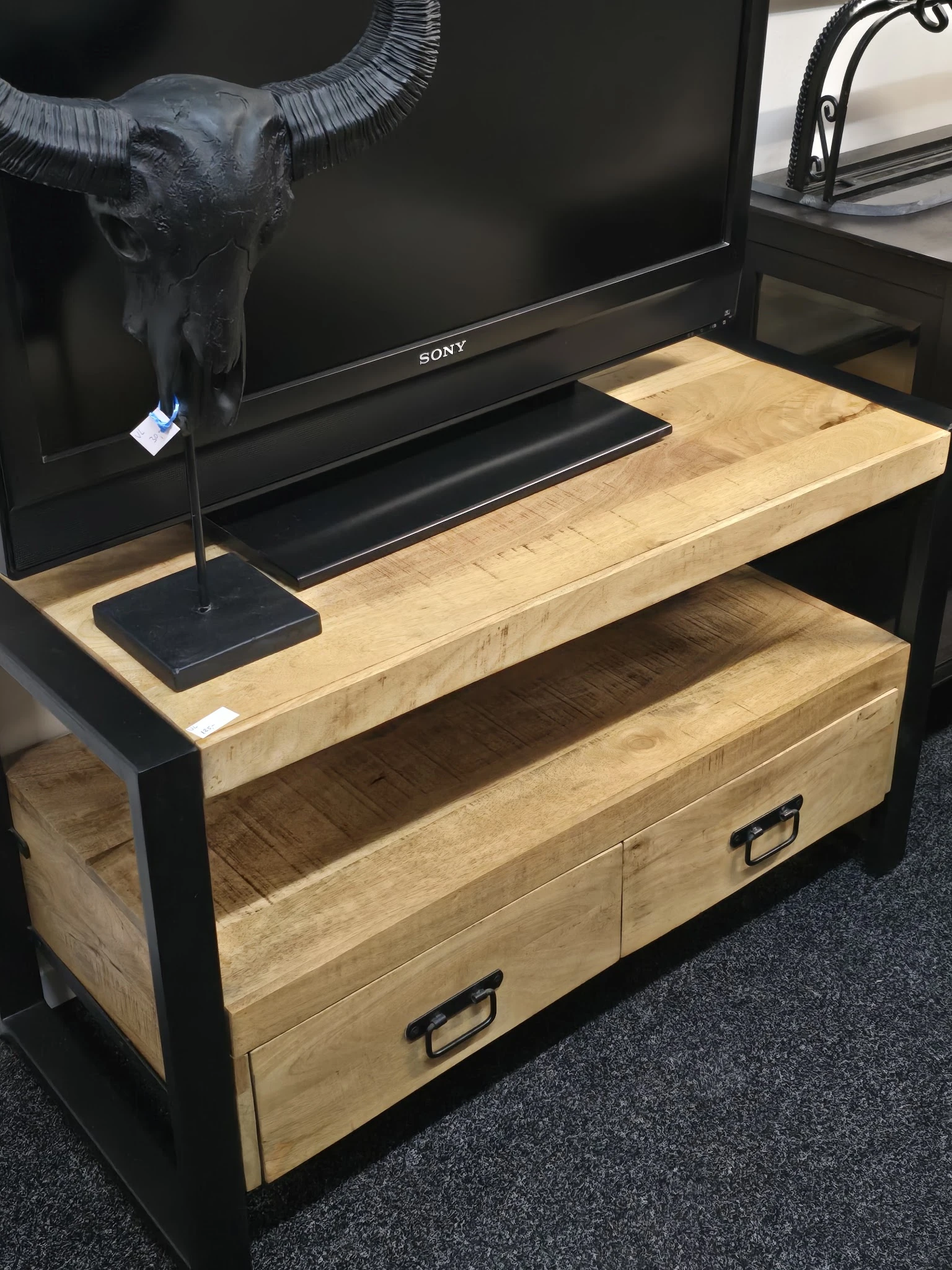 Houten tv-meubel met open vak en laden, opgesteld met Sony-televisie en accessoires