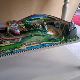 Elektrische racebaan speelgoedset met groene en rode banen, treinen en berglandschap.