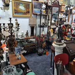 Overzicht van kringloopwinkelruimte met diverse meubels, decoratieartikelen, kandelaars, beelden en vintage spullen