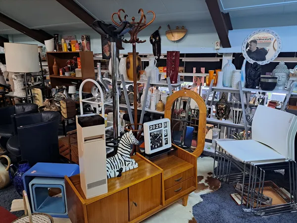 Binnenaanzicht van kringloopwinkel met diverse meubels, huishoudelijke artikelen en decoratie uitgestald op verschillende niv