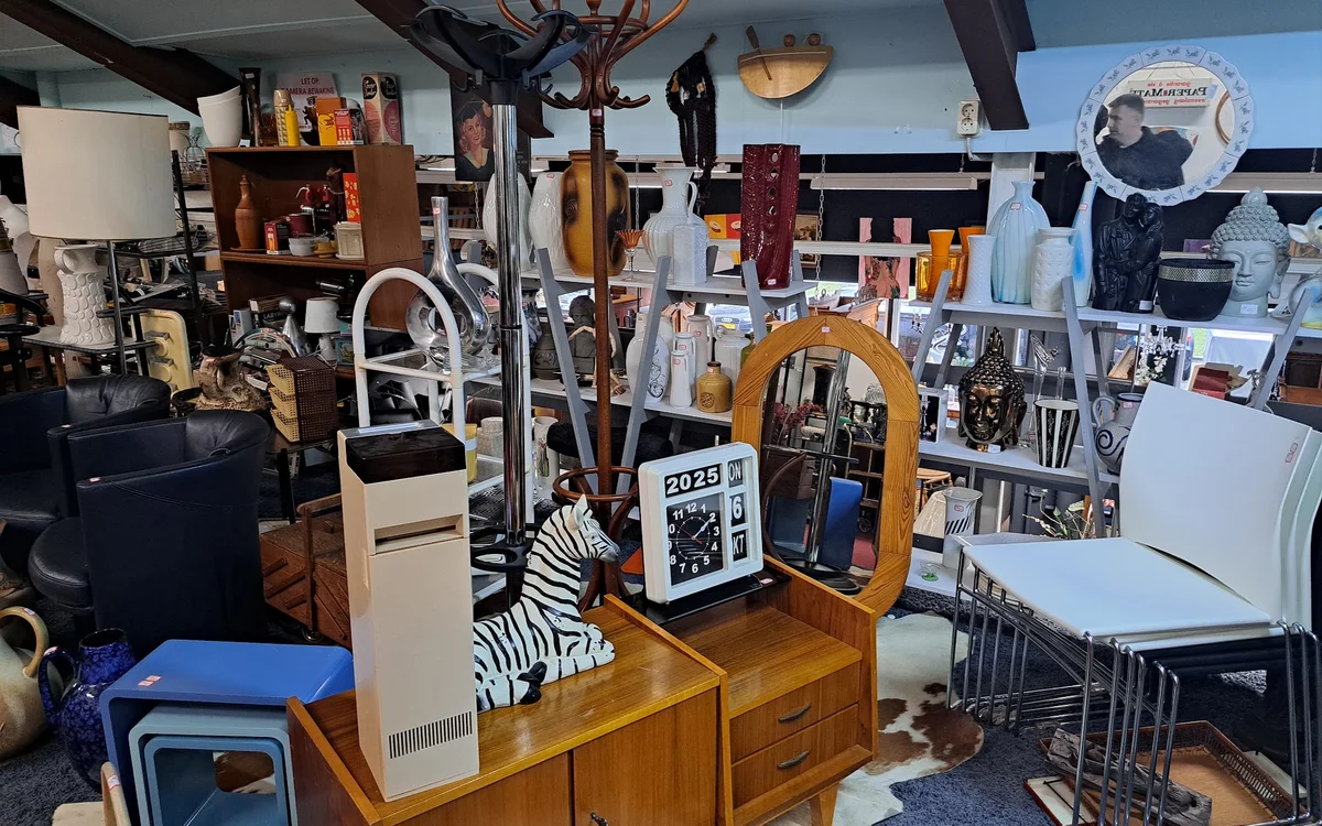 Binnenaanzicht van kringloopwinkel met diverse meubels, huishoudelijke artikelen en decoratie uitgestald op verschillende niv