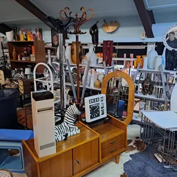 Binnenaanzicht van kringloopwinkel met diverse meubels, huishoudelijke artikelen en decoratie uitgestald op verschillende niv