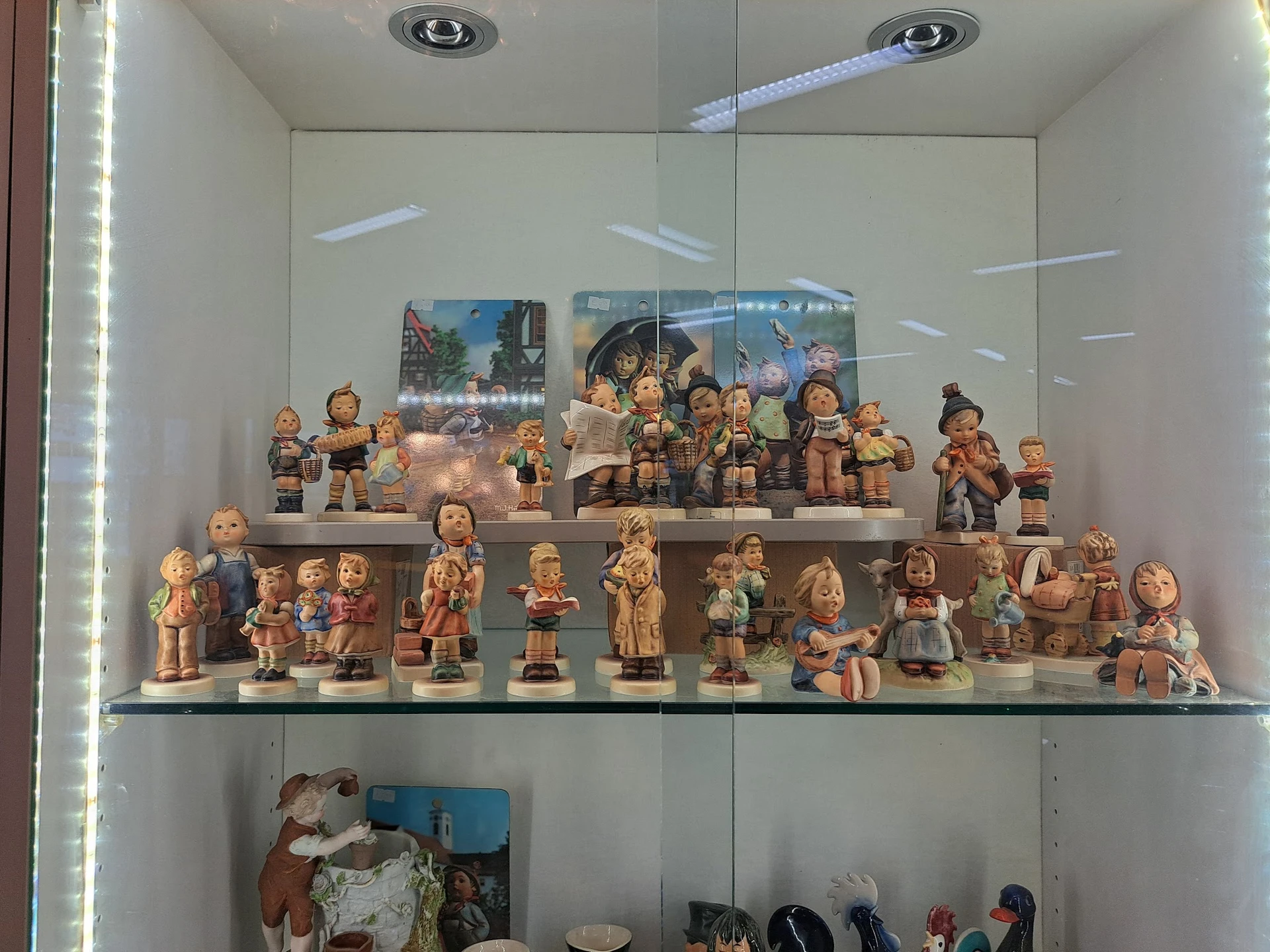 Glazen vitrine met verzameling keramische beeldjes en decoratiefiguren op meerdere niveaus