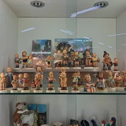 Glazen vitrine met verzameling keramische beeldjes en decoratiefiguren op meerdere niveaus
