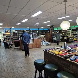 Winkelvloer van kringloopwinkel met diverse meubels, speelgoed en spullen uitgestald op tafels en stellingen