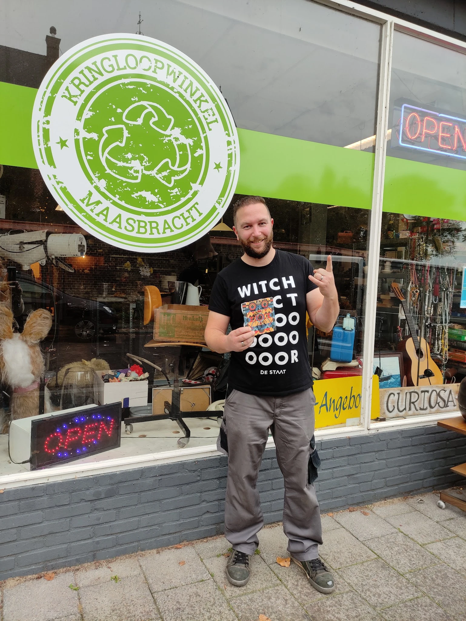 Man in zwart t-shirt staat voor de winkelruit en poseeert voor de camera