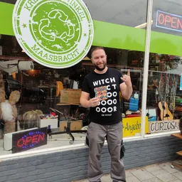 Man in zwart t-shirt staat voor de winkelruit en poseeert voor de camera