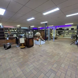 Winkelvloer van kringloopwinkel met stellingen, vitrines en diverse spullen langs de zijkanten