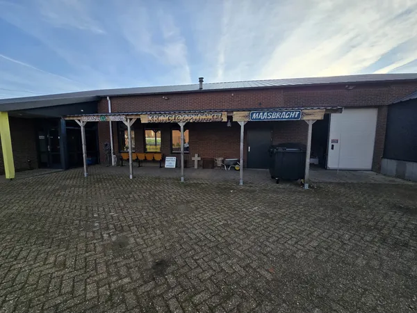 Voorkant van kringloopwinkel met bakstenen gevel, overkapping en ingang