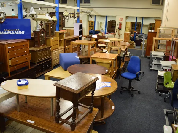 Winkelvloer met houten meubelen, tafels, stoelen en kastjes uitgestald, blauw logo zichtbaar