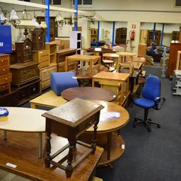 Winkelvloer met houten meubelen, tafels, stoelen en kastjes uitgestald, blauw logo zichtbaar